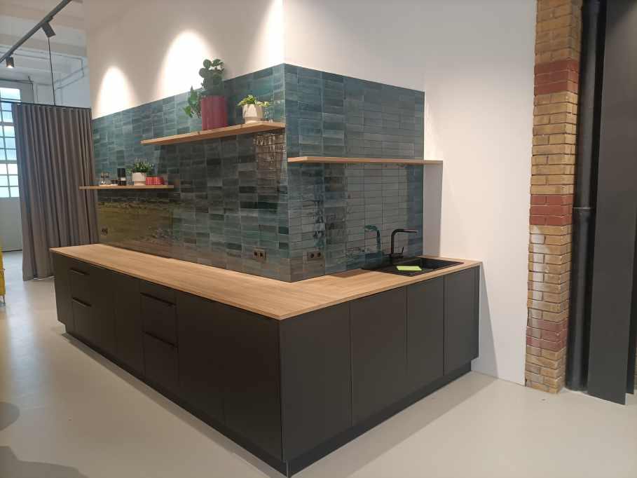 Schwarze Kücheninsel mit Holzplatte und grüner Fliesenwand im Loft – Referenz System & Idee